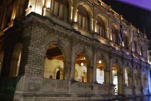 Um edifício histórico com janelas em arco e fachada de tijolos.