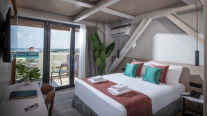 Een hotelkamer met een bed, een bureau, een stoel, een balkon met uitzicht en een airconditioning.