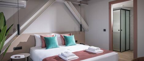 Une chambre d’hôtel moderne avec un lit, des oreillers, une table de chevet et une plante en pot.