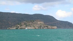 Een uitzicht op de kust met een historisch gebouw op een heuvel, omringd door water en bergen.