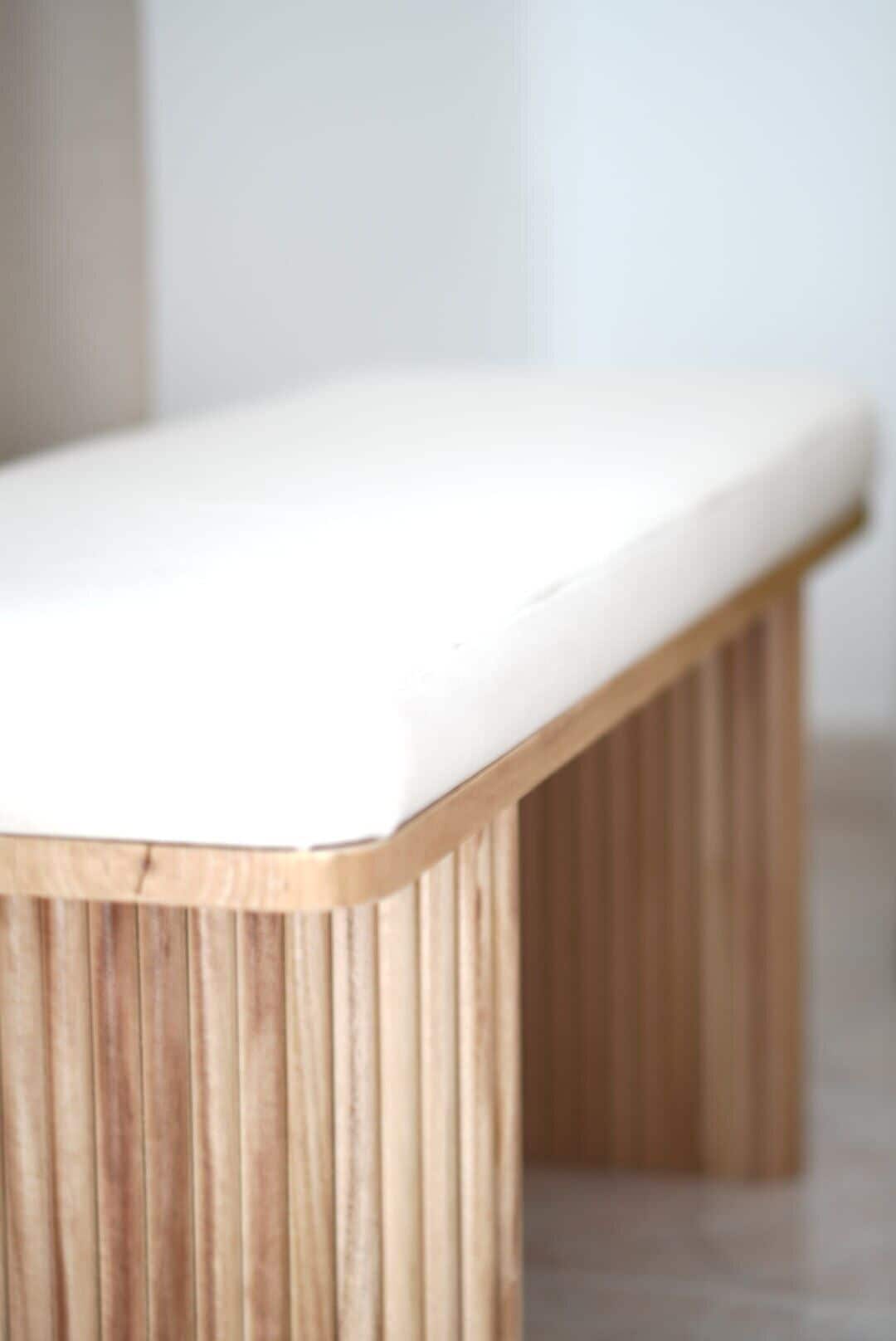 Un banc en bois avec un coussin blanc.
