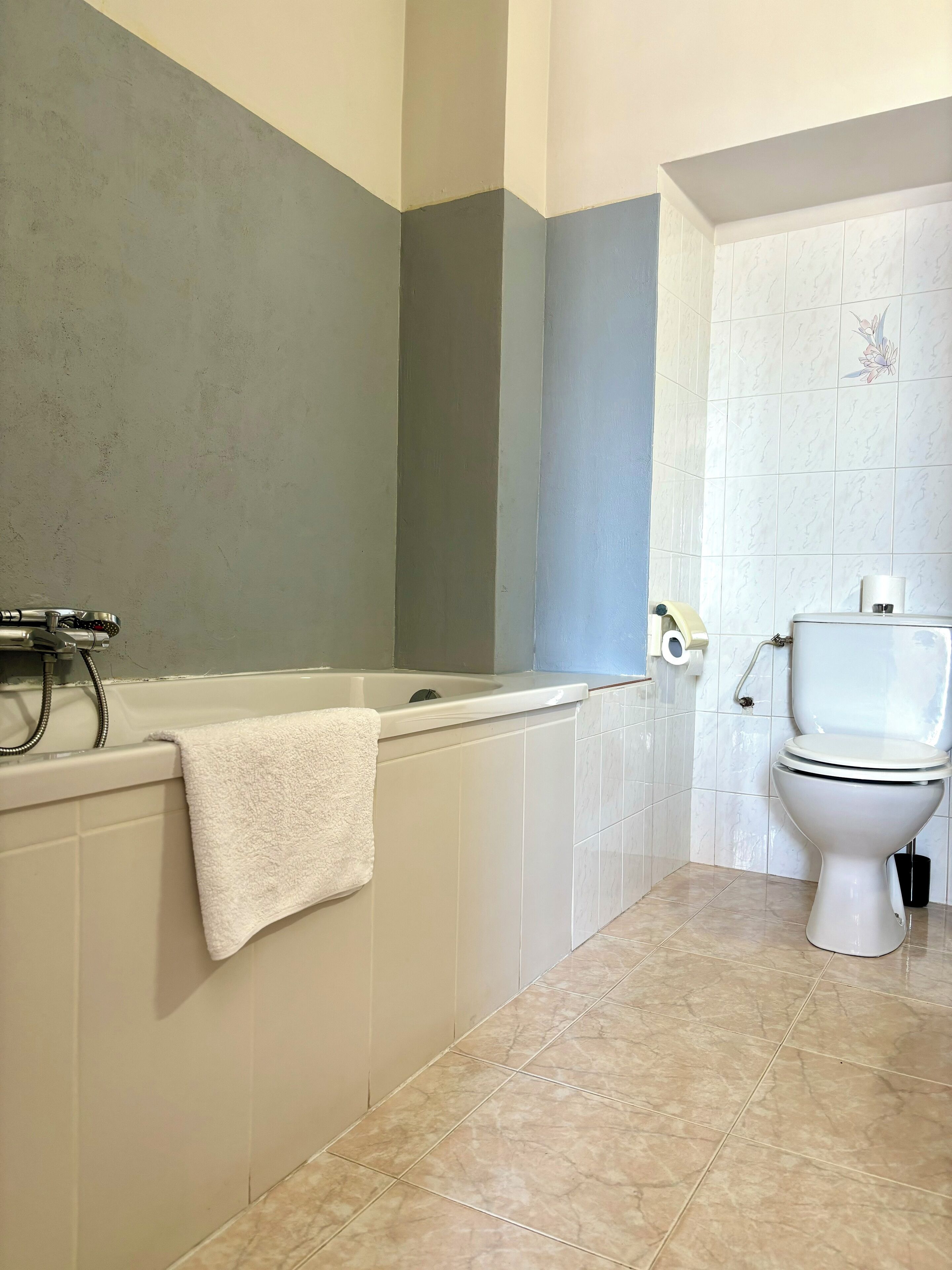A bathroom with a bathtub, toilet, and tiled floor.