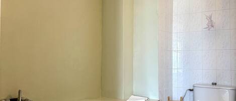 Un baño con bañera, inodoro y un taburete de madera.
