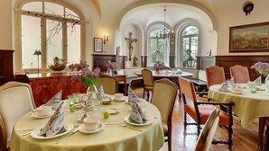 Un comedor con mesas redondas, sillas y una lámpara de araña.