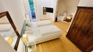 Un dormitorio con dos camas, un armario de madera, una mesa de vidrio con una planta y vistas al exterior.