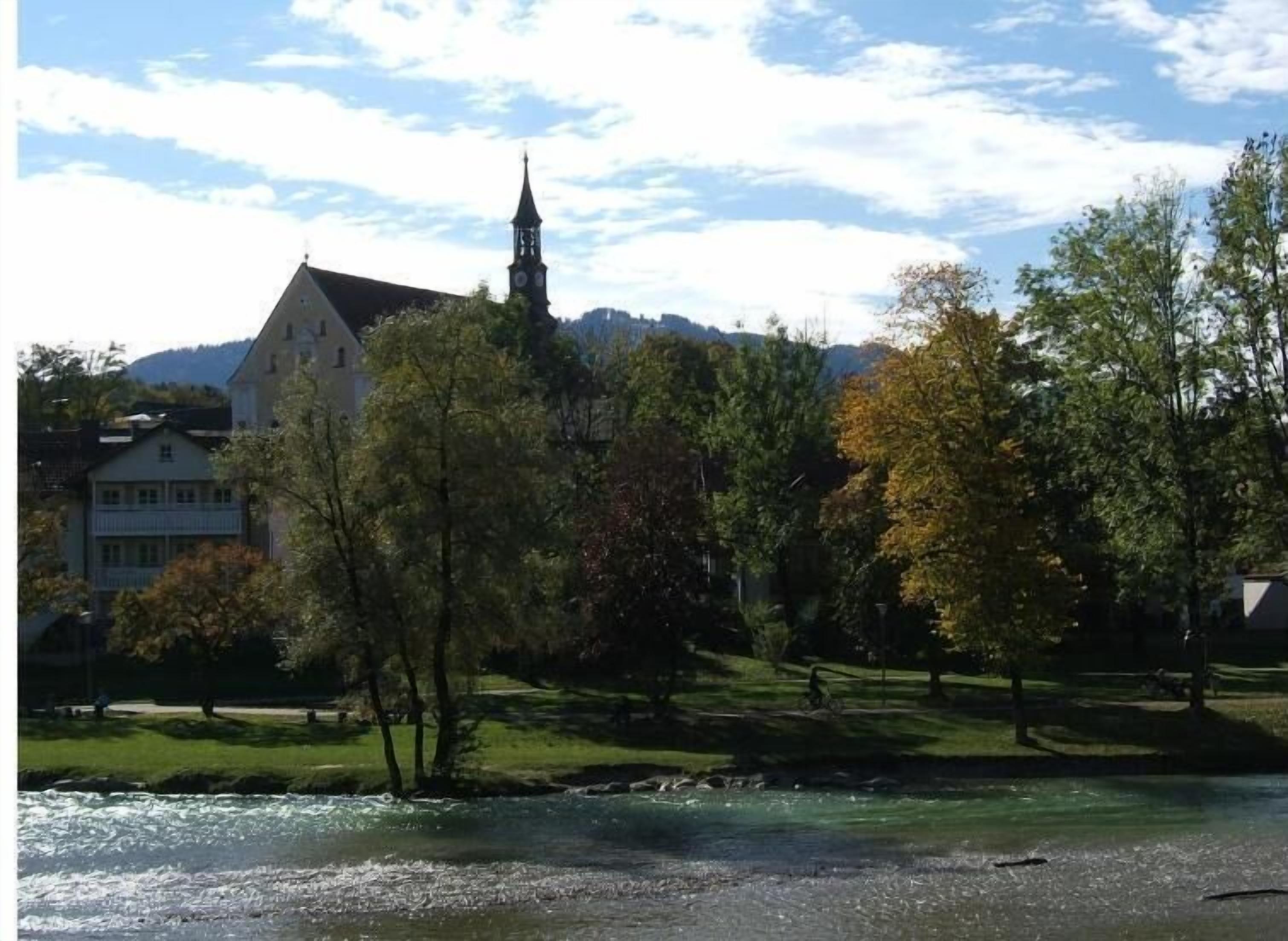 A river with a church and residential buildings in the background.