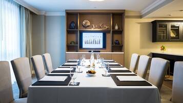A conference room with a long table, chairs, a screen displaying a graph, and decorative items on shelves.