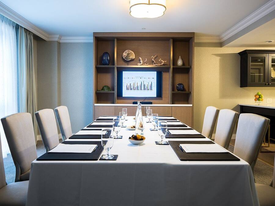 A conference room with a long table, chairs, a screen displaying a graph, and decorative items on shelves.