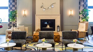 Un vestíbulo de hotel con chimenea, zona de estar y apliques decorativos.