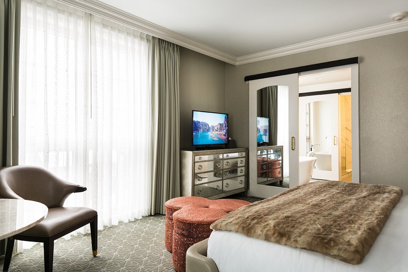 A hotel room with a bed, a TV, a desk, and a chair.