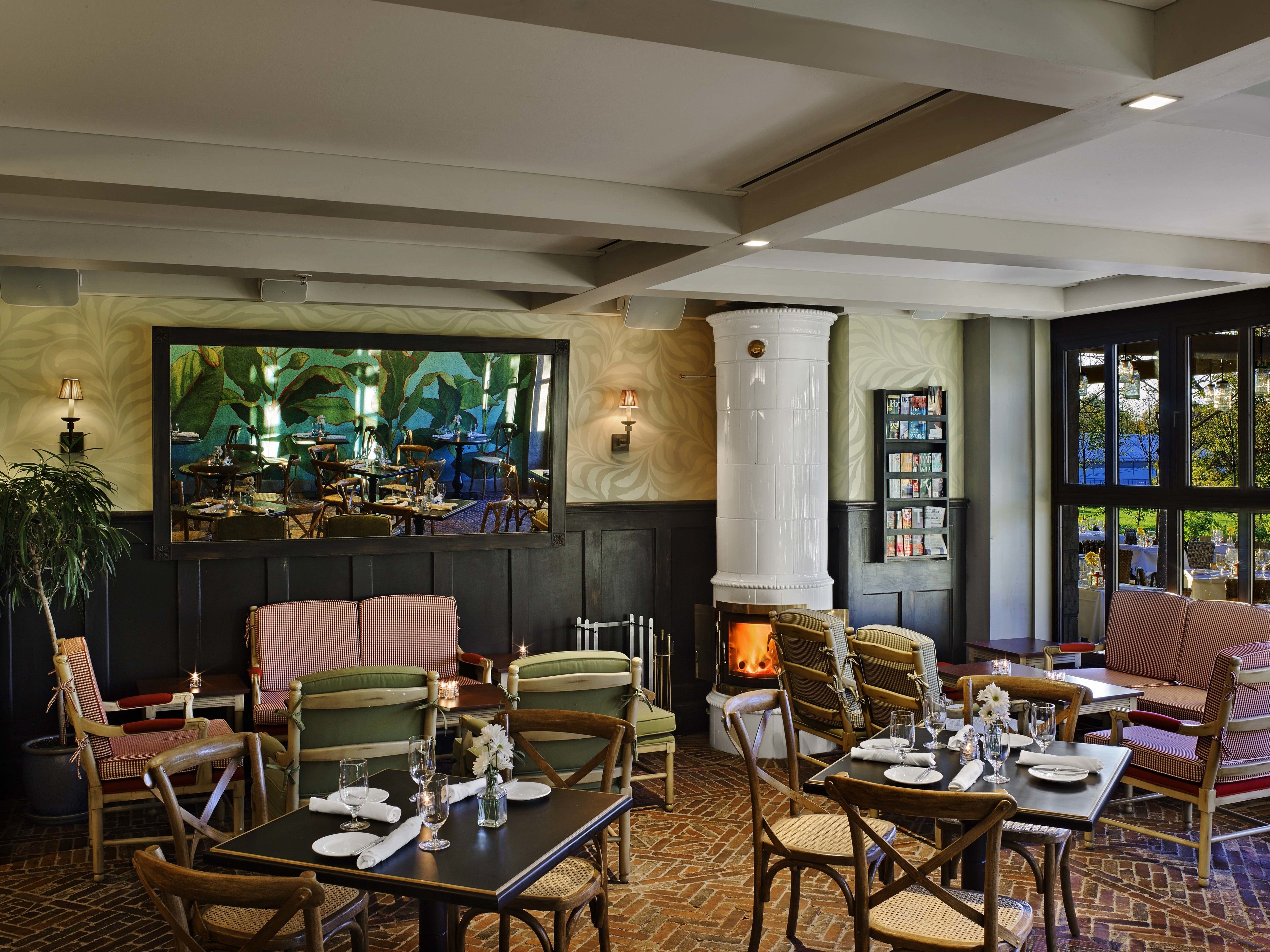 A restaurant with brick flooring, wooden furniture, and a fireplace.