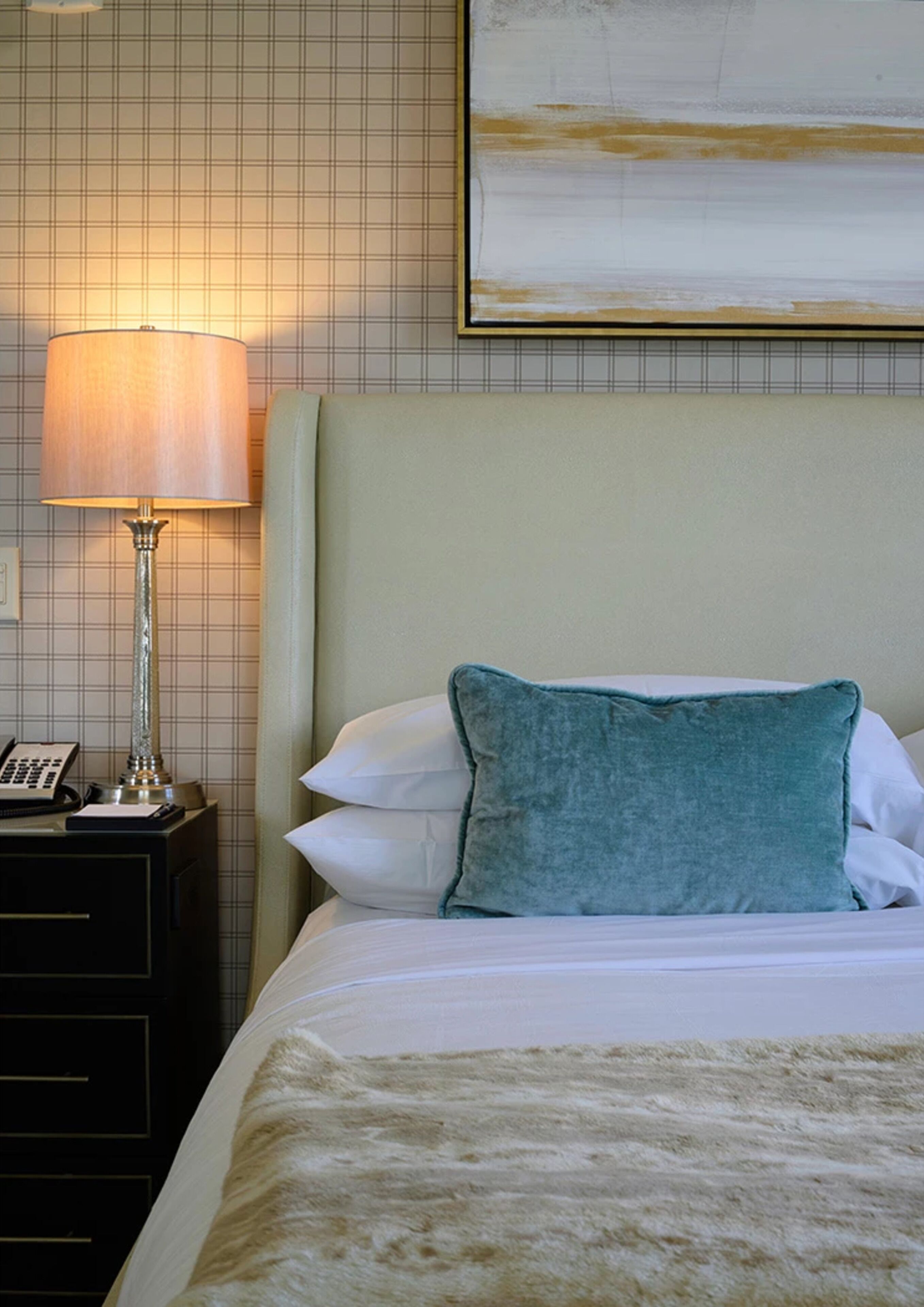 Una habitació d'hotel amb un llit, una taula de nit amb una làmpada i un quadre a la paret.