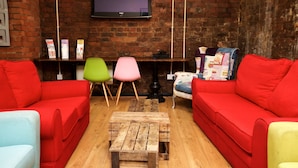 Una sala de estar con sofás rojos, una mesa de centro de madera y un televisor montado en una pared de ladrillo.