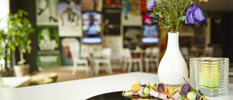 A dining table with a vinyl record, a vase with purple flowers, and a glass of water.