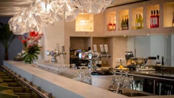 A bar area with a long counter, multiple taps, and a variety of bottles in the background.