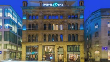 Un edificio storico con il cartello 'Motel One', ampie finestre e uno stile architettonico classico.