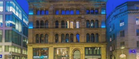 A historic building with a 'Motel One' sign, large windows, and a classic architectural style.