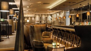 A modern bar area with high stools, a bar counter, and ambient lighting.