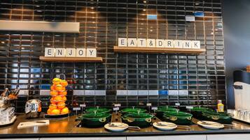 Ein reichhaltiges Buffet mit einem Schild, auf dem 'ENJOY EAT & DRINK' steht, und einer Ansammlung von Orangen.