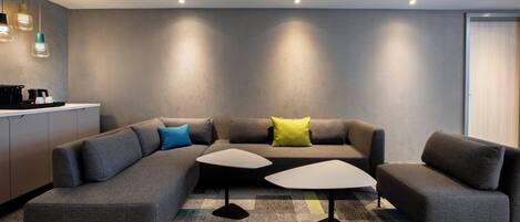 A modern living room with a sectional sofa, two side tables, and a kitchen area in the background.