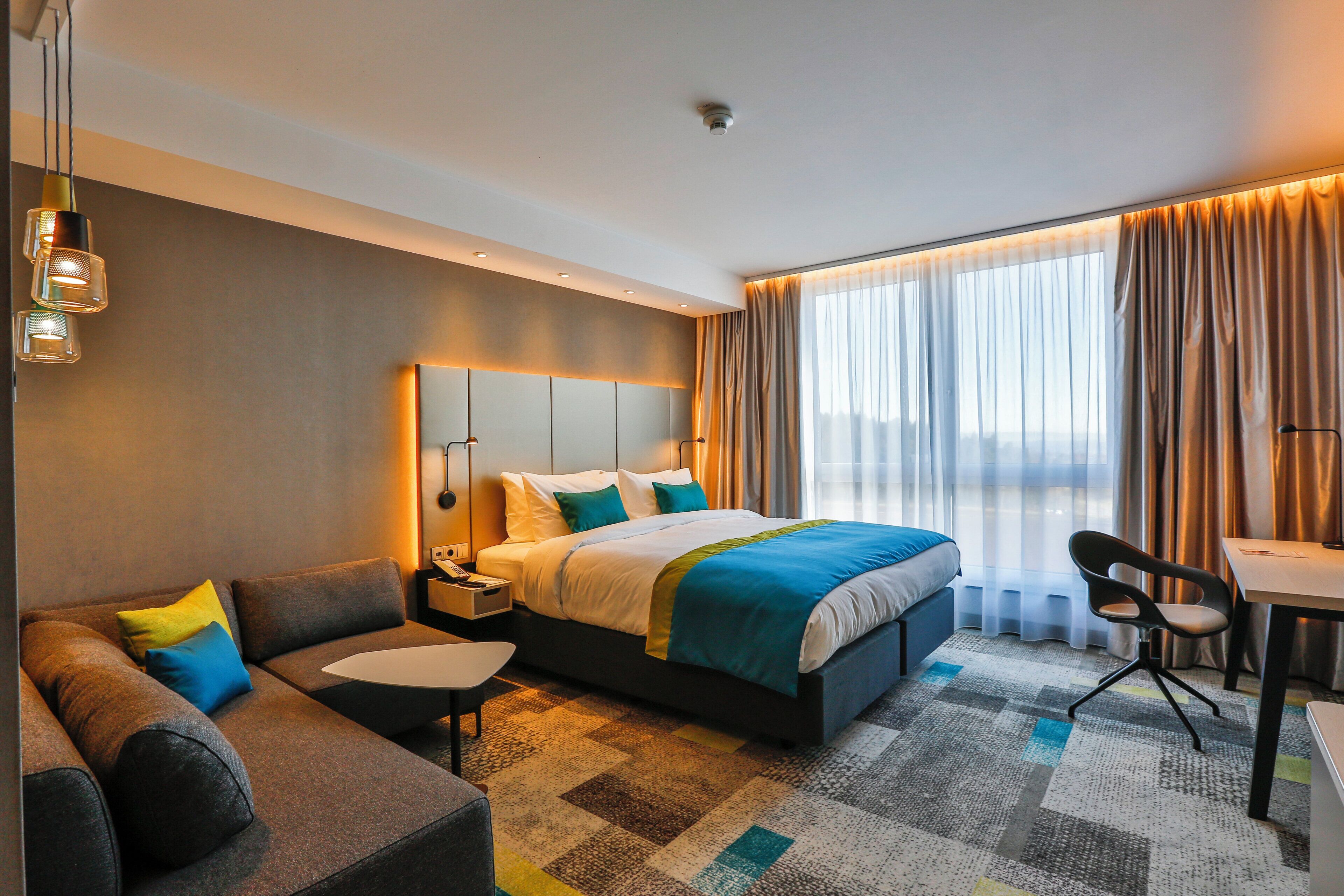 Een moderne hotelkamer met een groot bed, een sofa, een bureau en een stoel.