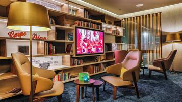 A hotel lounge with leather armchairs, a television, and bookshelves.