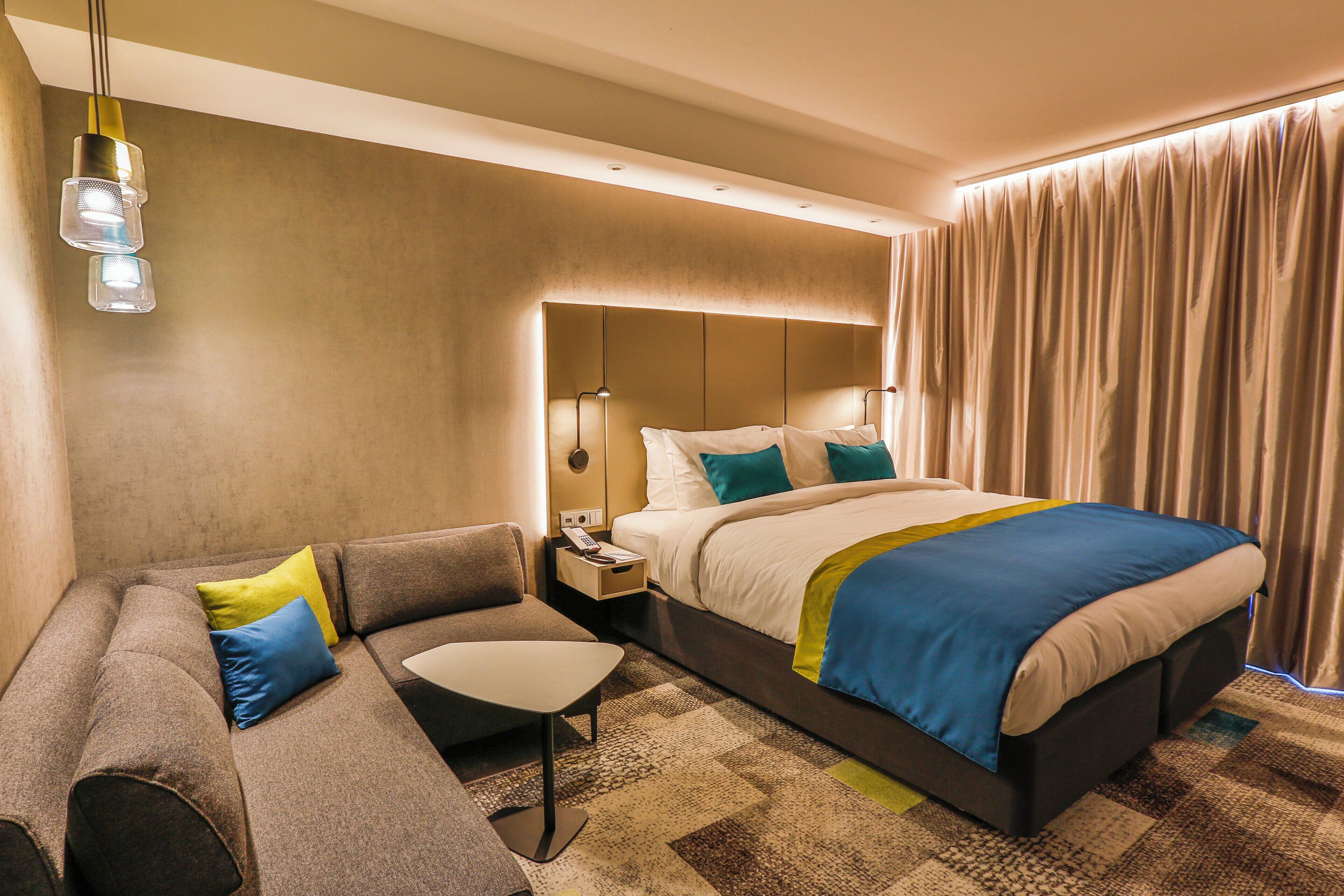 Ein Hotelzimmer mit Bett, Sofa, Nachttisch und Lampe.