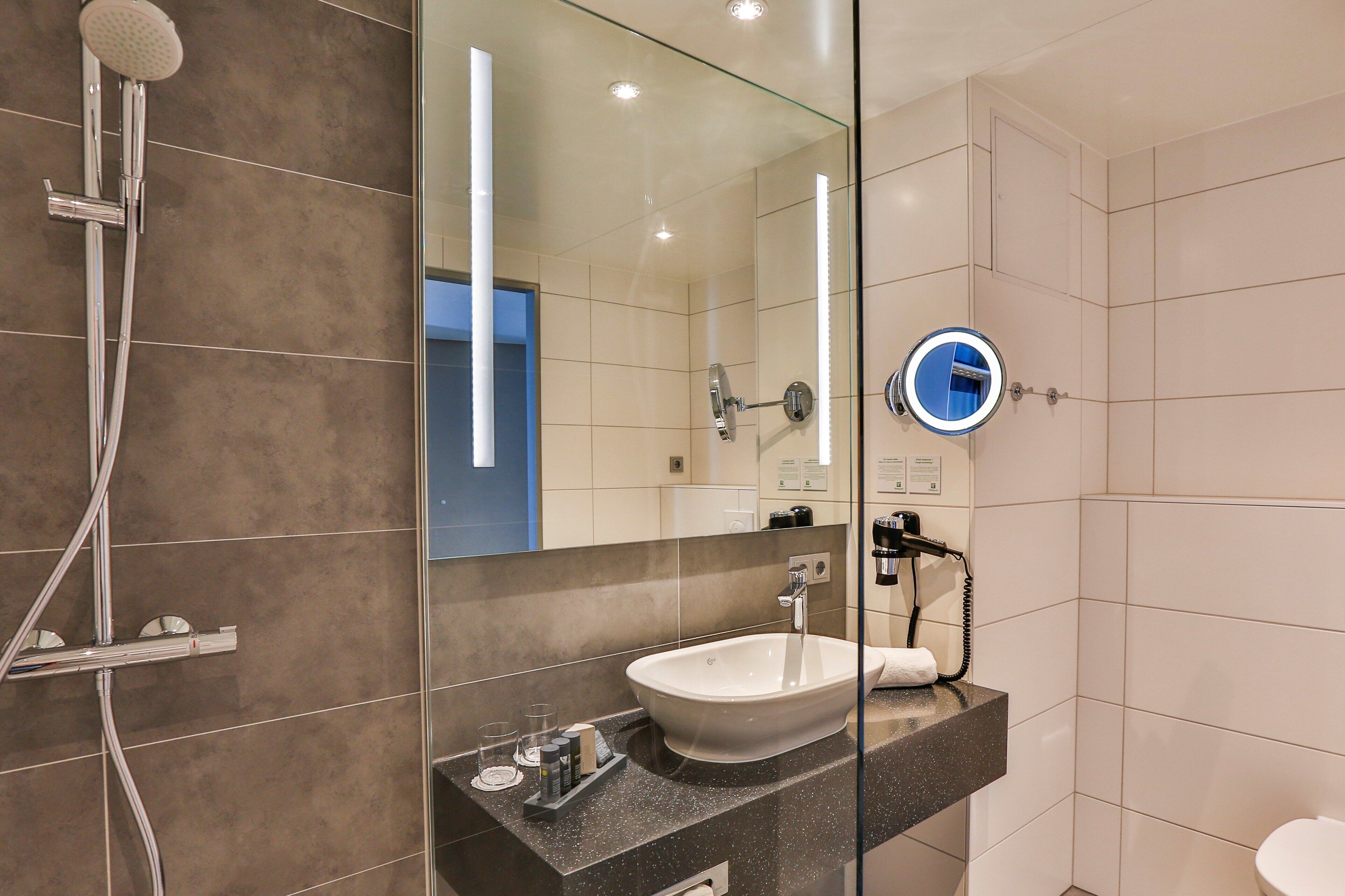 A modern bathroom with a glass shower enclosure, a sink with a mirror, and a toilet.