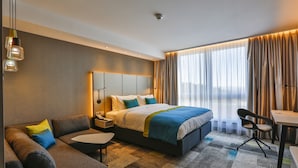A modern hotel room with a large bed, a sofa, a desk, and a chair. - Holiday Inn Villingen - Schwenningen by IHG (Villingen-Schwenningen)