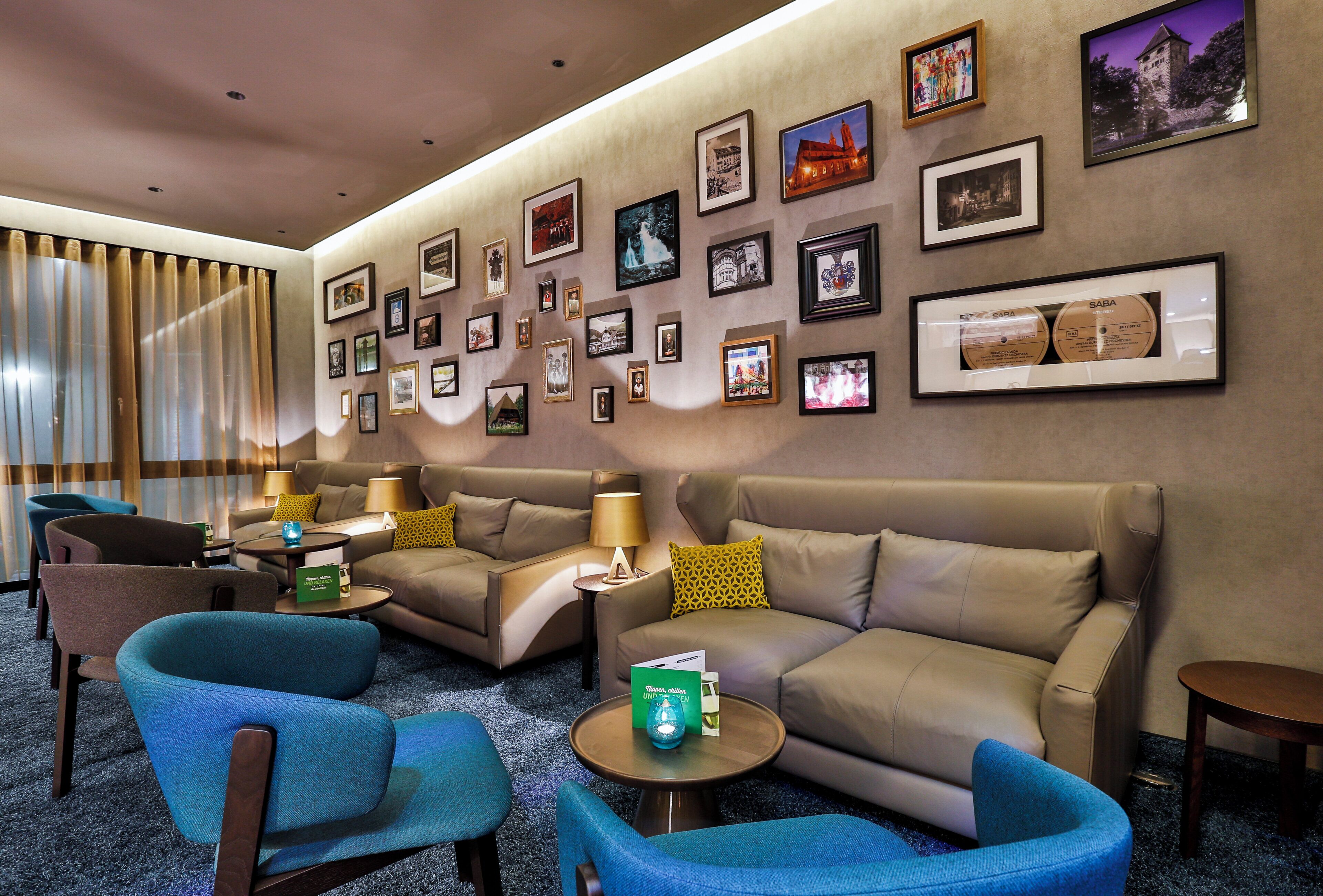 Un hall d’hôtel avec un espace salon, des tableaux encadrés aux murs et un sol recouvert de moquette.
