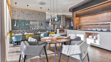 Un interior de restaurante moderno con una zona de bar, arreglos de asientos y un mostrador tipo bufé.