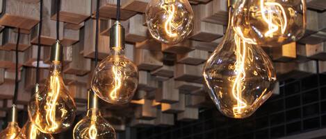 Multiple hanging light bulbs with a clear filament design, suspended from a wooden structure.