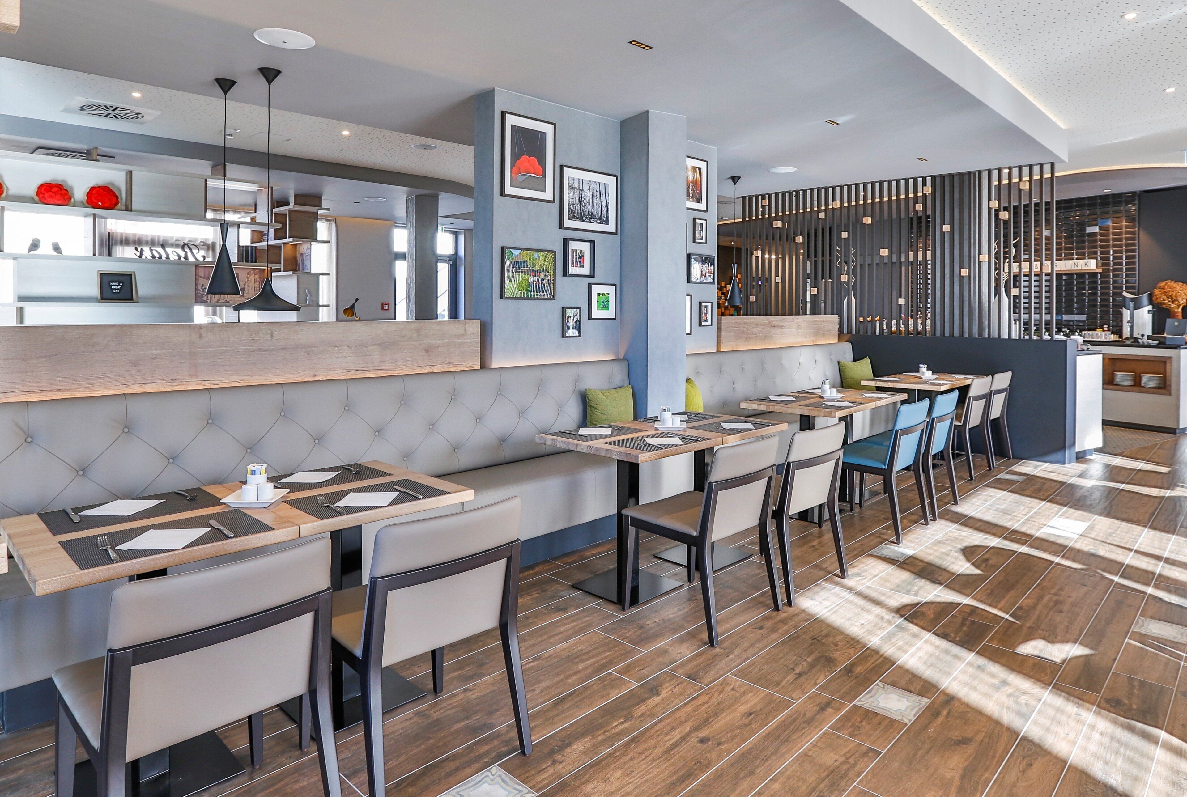 A modern cafe with a long counter, cushioned seating, and a bar area.