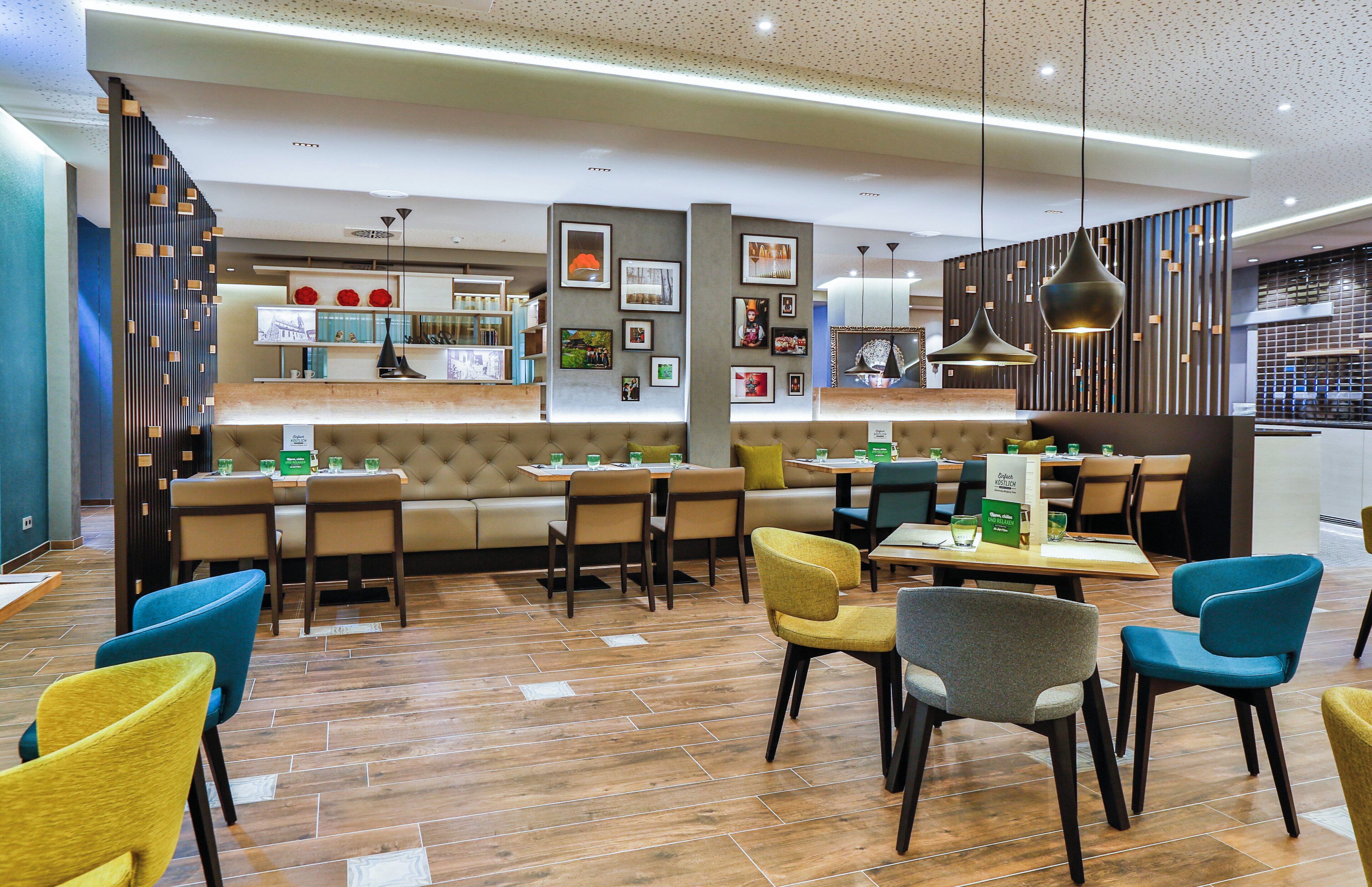 Un interior de restaurante moderno con diferentes opciones de asiento, como cabinas y mesas, y una zona de bar al fondo.