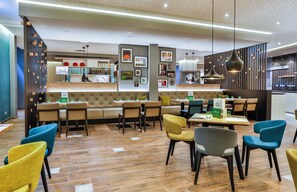 Un interno ristorante moderno con varie opzioni di posti a sedere, tra cui cabine e tavoli, e un'area bar sullo sfondo.