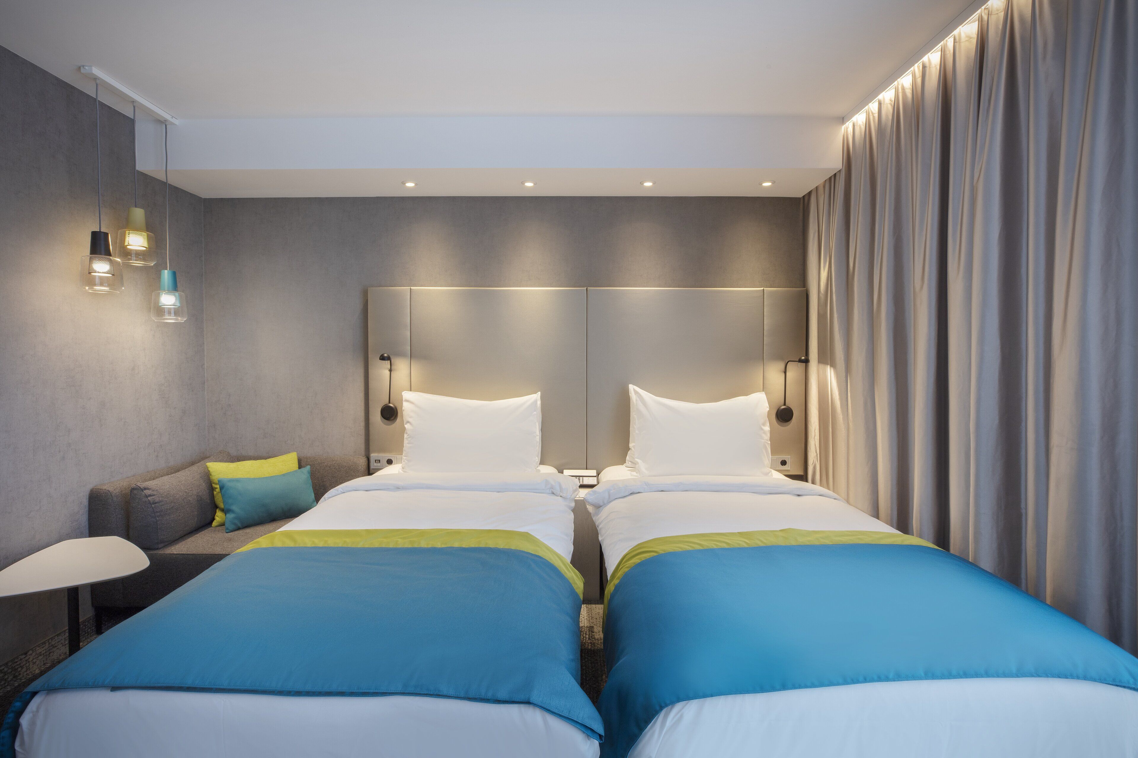 A hotel room with two beds, a sofa, and a lamp.