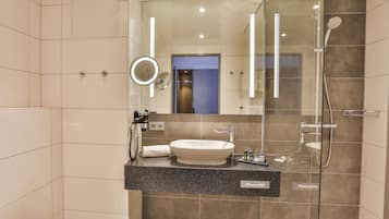 Un baño moderno con una bañera independiente, una ducha con cerramiento de vidrio y un tocador con un espejo grande.