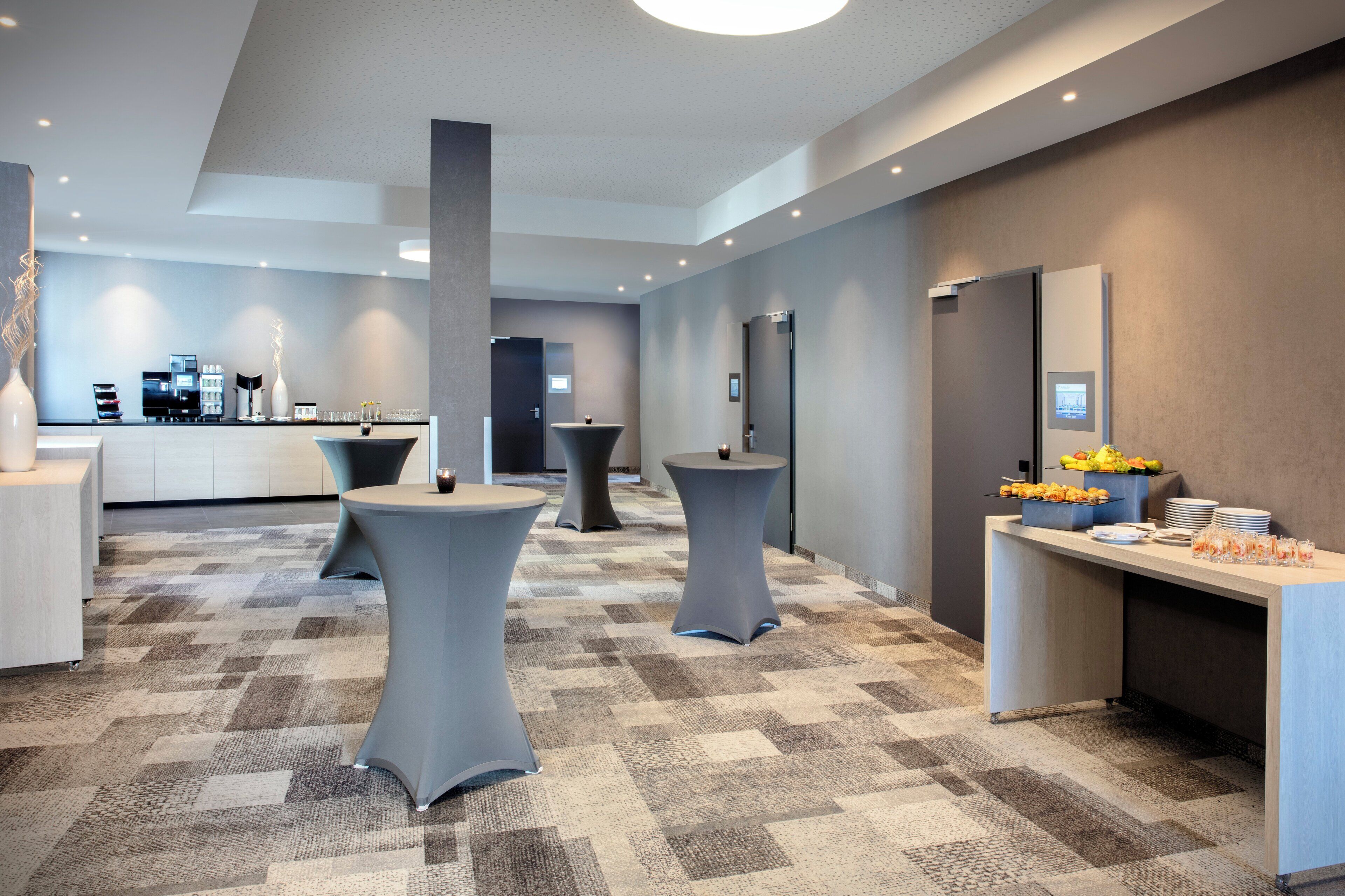 A modern hotel lobby with a reception desk, seating areas, and a buffet setup.