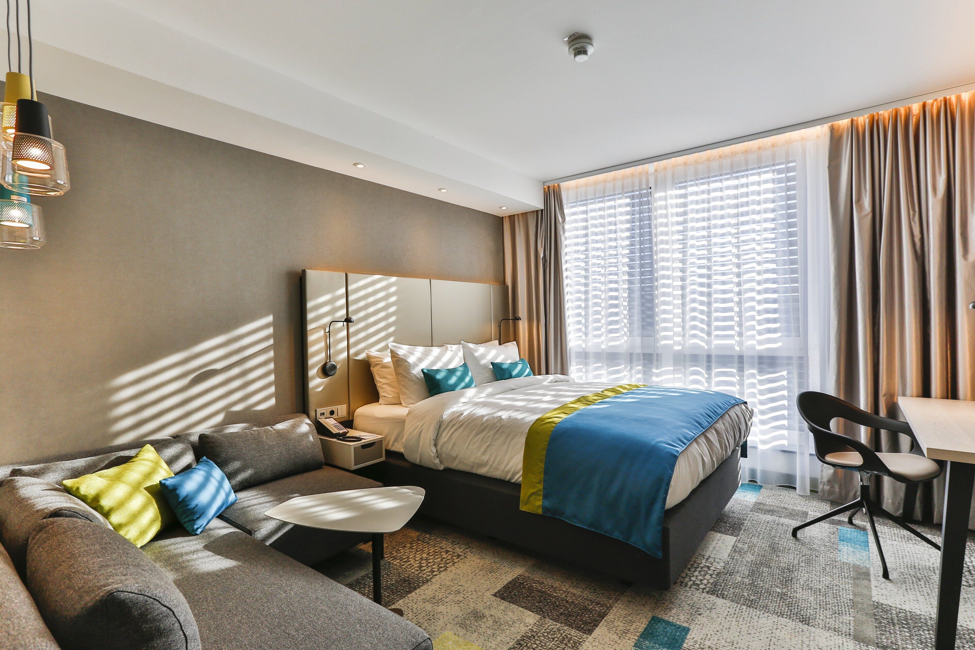 Una habitación de hotel moderna con una cama grande, un sofá, un escritorio y una silla.