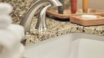 A bathroom sink with a modern faucet, a granite countertop, and a mirror above it.