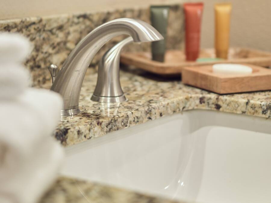 A bathroom sink with a modern faucet, a granite countertop, and a mirror above it.
