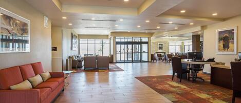 A spacious lobby with a red sofa, a patterned rug, and a reception desk with computers.
