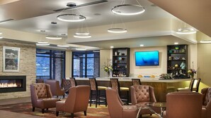 A modern bar area with leather chairs, a fireplace, and a large TV screen. - The Hotel at Sunland Park Casino El Paso, an Ascend Collection Hotel (Sunland Park)