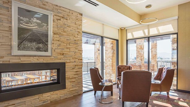 A modern lounge area with a fireplace, comfortable seating, and large windows offering a view of the city. - The Hotel at Sunland Park Casino El Paso, an Ascend Collection Hotel (Sunland Park)