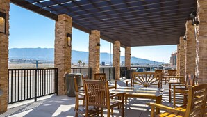 An outdoor patio with wooden furniture and stone pillars, overlooking a mountainous landscape. - The Hotel at Sunland Park Casino El Paso, an Ascend Collection Hotel (Sunland Park)