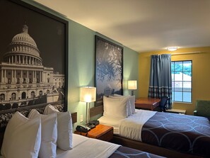 Une chambre d’hôtel avec deux lits, une table de chevet, une lampe, une fenêtre avec des rideaux et une fresque murale représentant le Capitole.