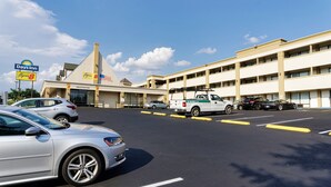 A Days Inn with a Super 8 sign, a parking lot with several cars, and a building with multiple floors and a flat roof.