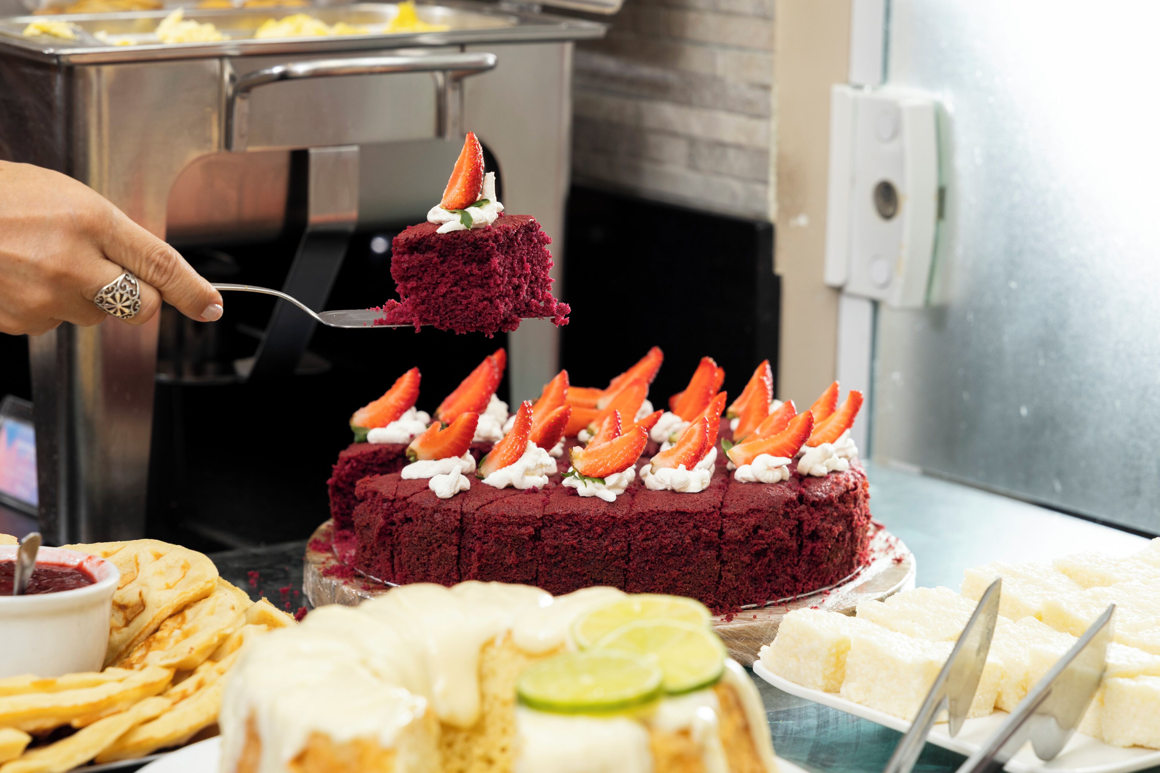 Um buffet de sobremesas com um bolo de veludo vermelho coberto com morangos e chantilly.
