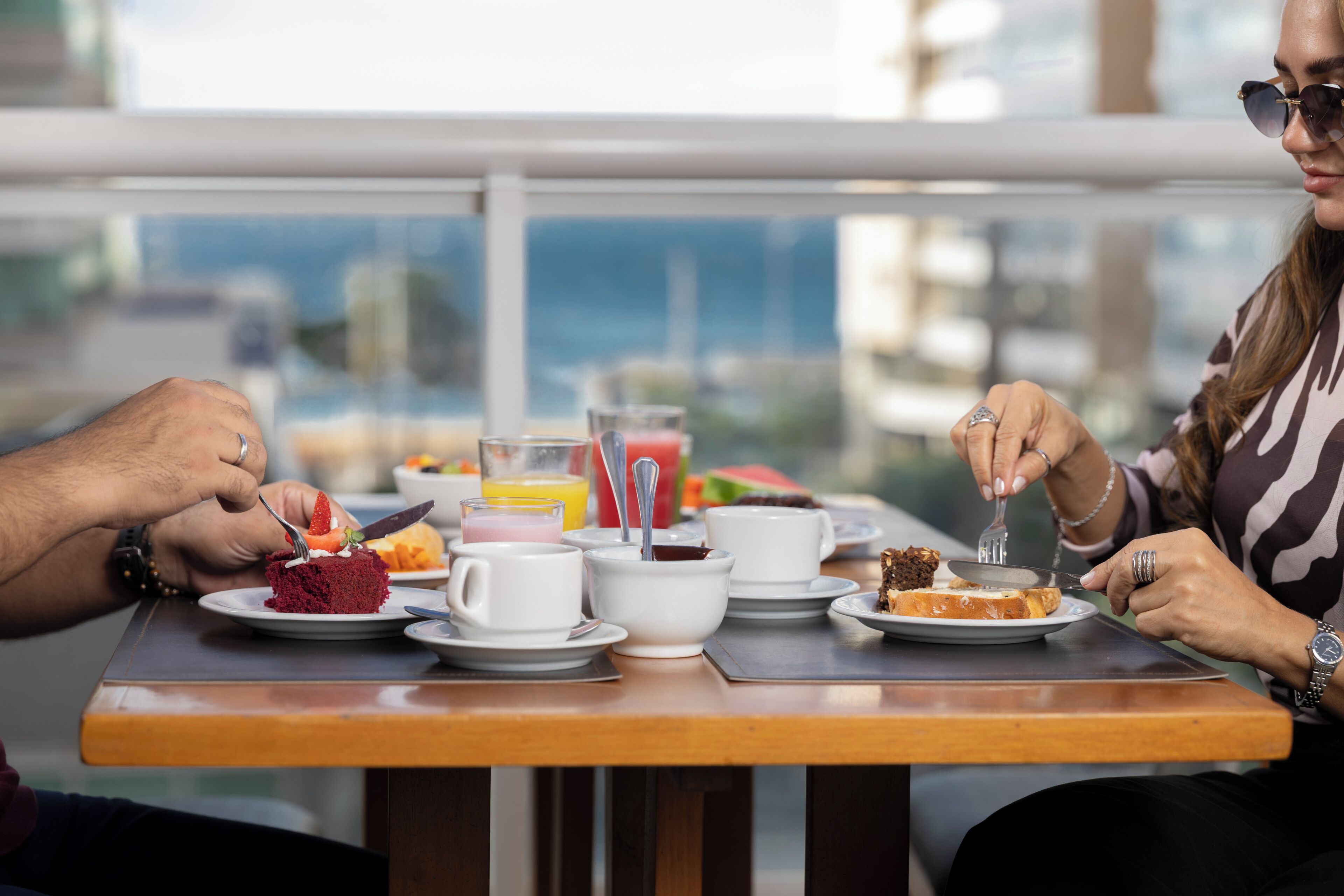 Una mesa de comedor con platos de comida, tazas y un vaso de jugo.