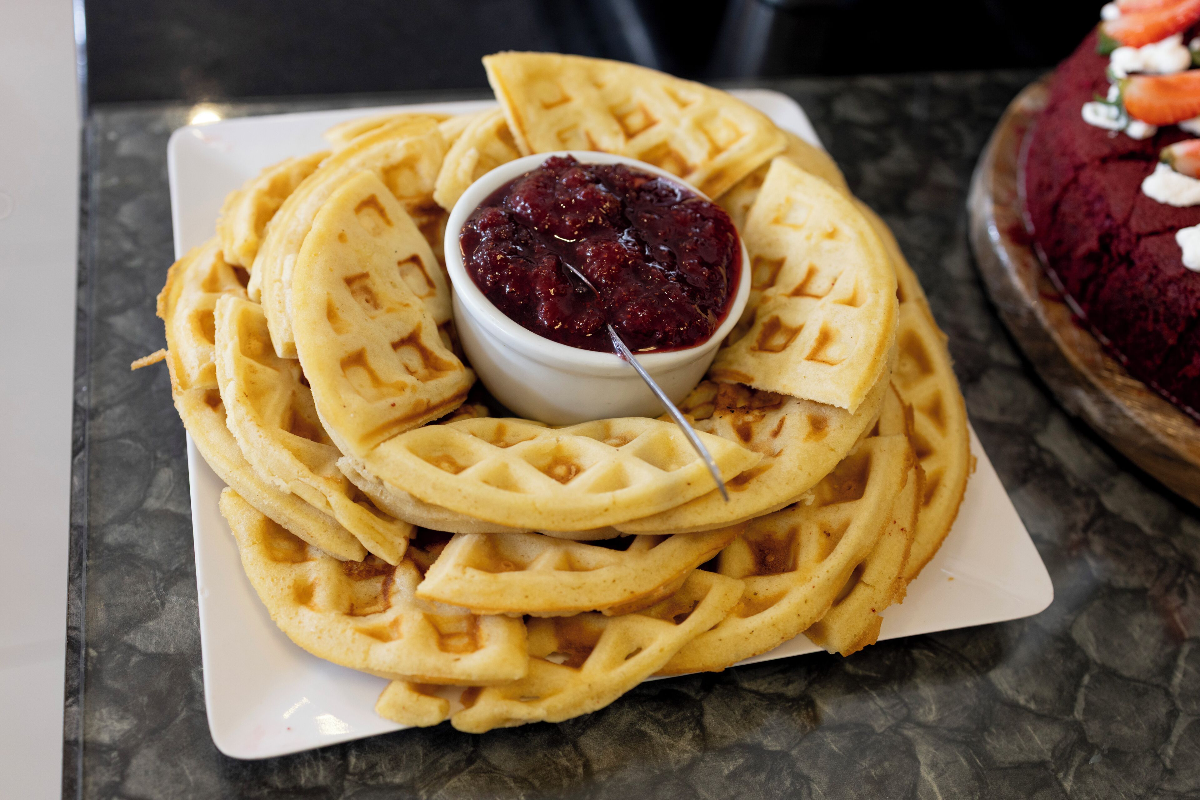 Ein Teller Waffeln mit einer Schale Marmelade in der Mitte.